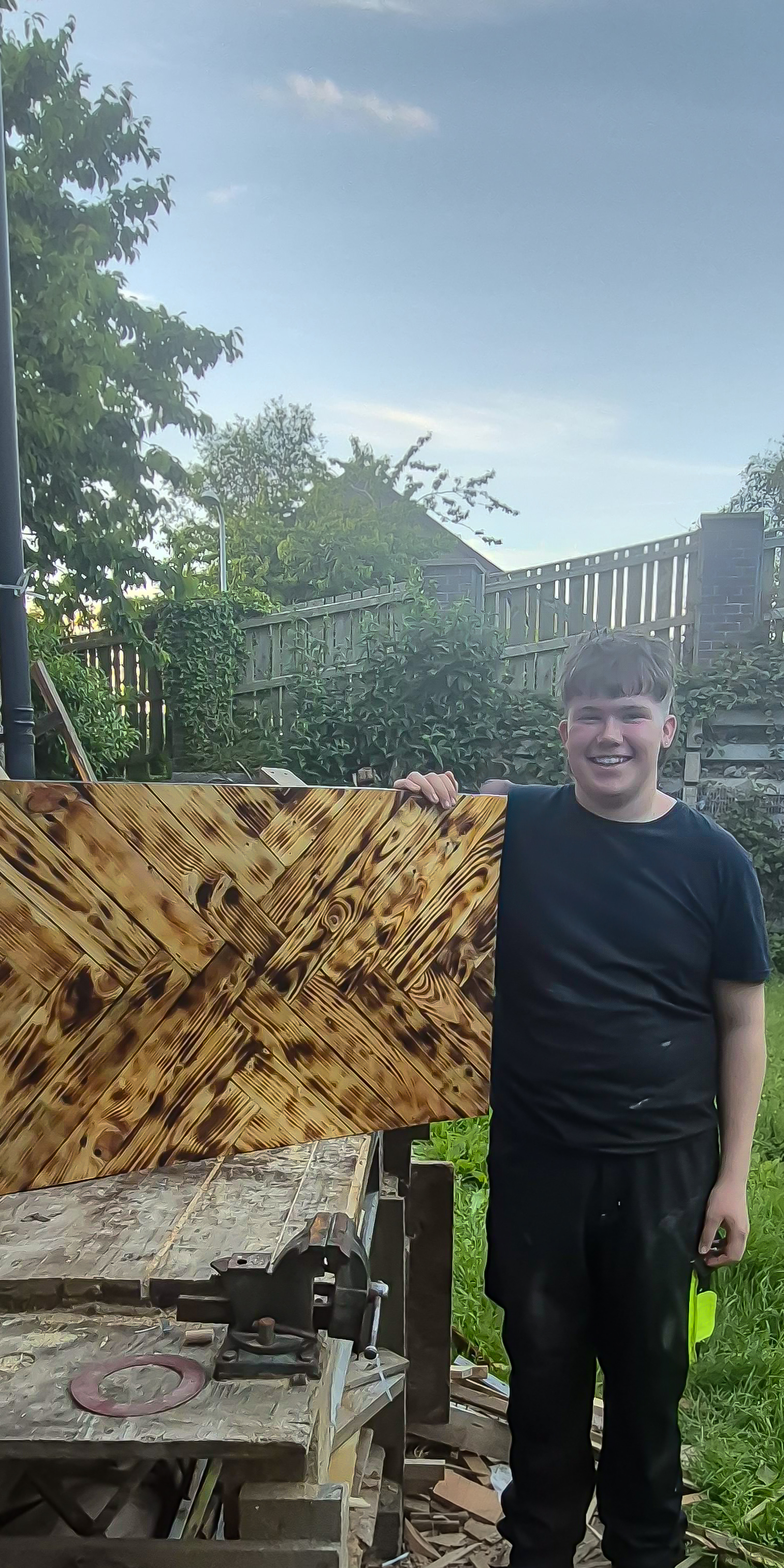 Mason Hughes holding his handcrafted herringbone table